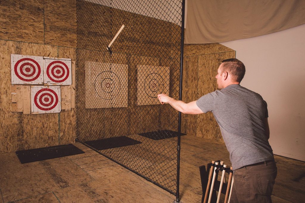 A man throwing an axe at targets in an indoor range.