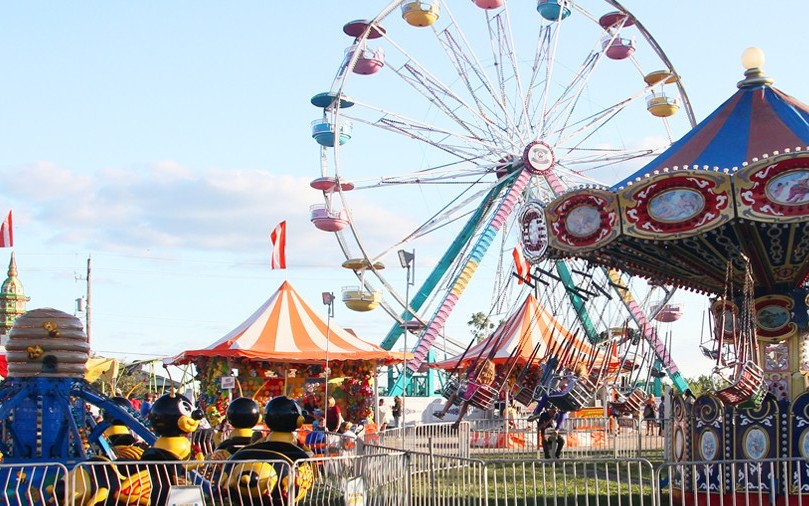 Fairgrounds in the daytime with carousel and ferris wheel.