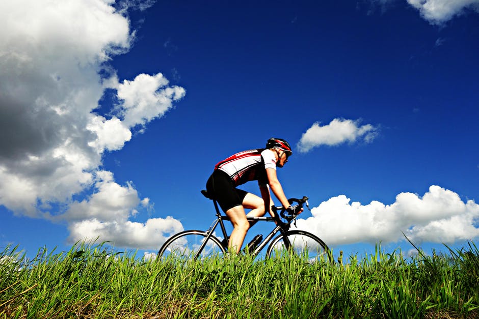 Cyclist cycling along rural road with blue skies